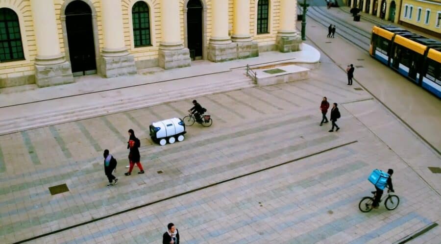 Ona riding on the streets of Debrecen with pedestrians and cyclists around it