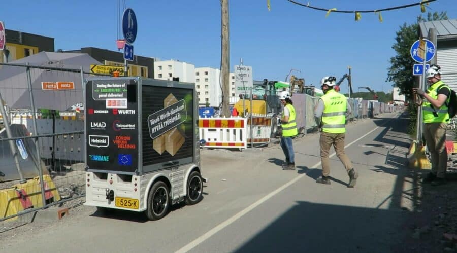 The robot on a road surrounded by three construction workers 